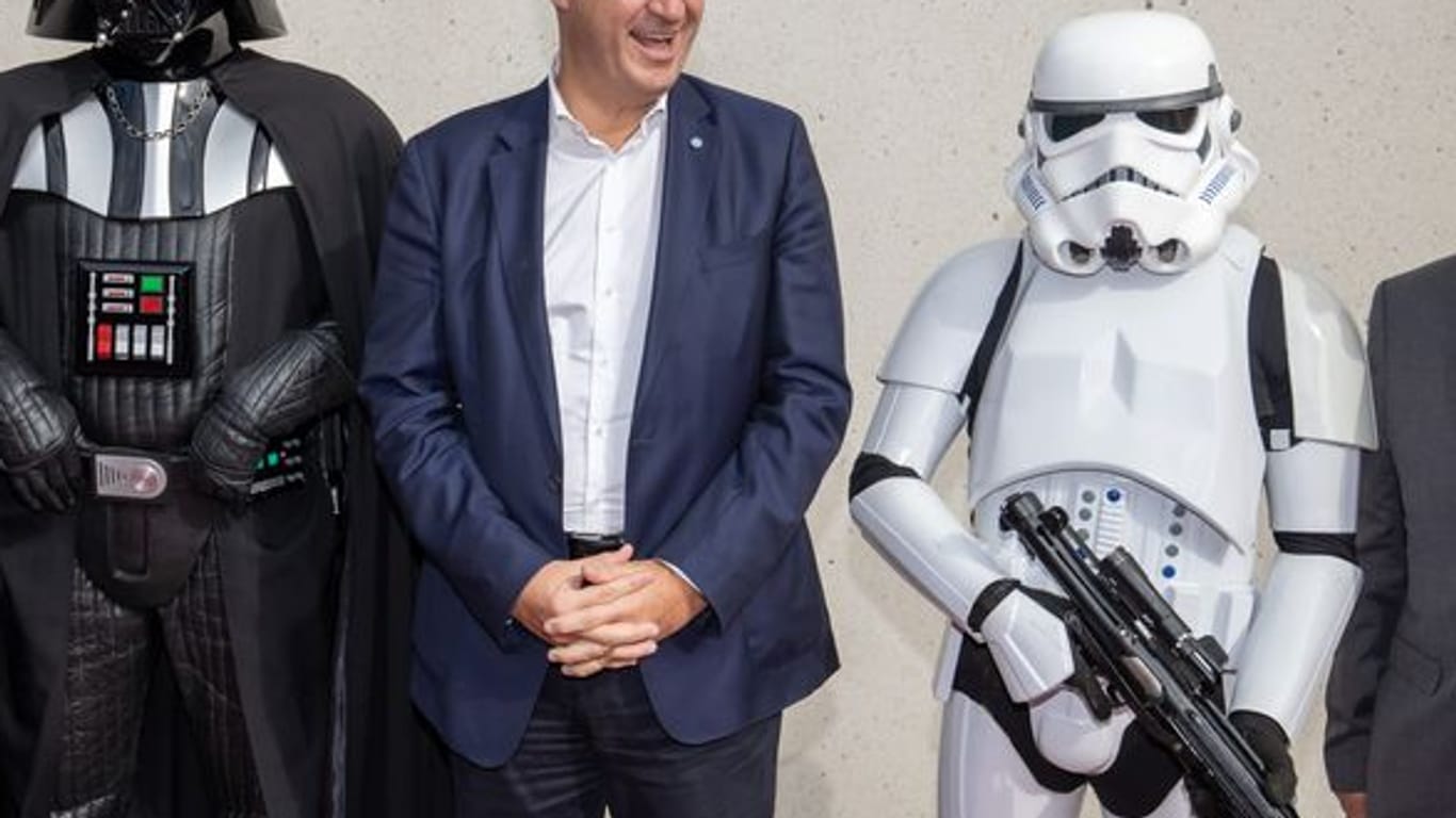 Markus Söder (M), CSU-Parteivorsitzender und Ministerpräsident von Bayern, steht zwischen Akteuren, die verkleidet als Figuren aus dem Film "Star Wars" sind: Das Museum stellt Zukunftsthemen vor und diskutiert ethische Fragen.