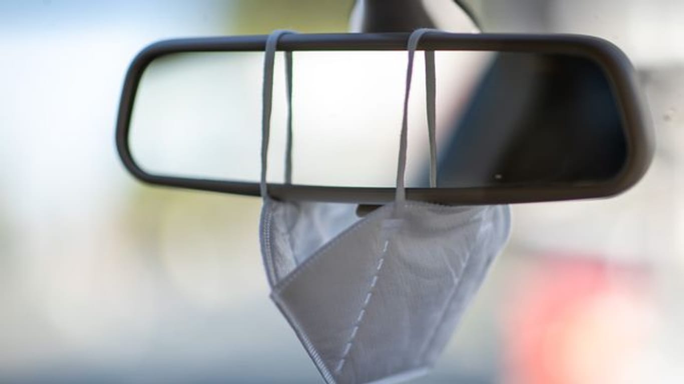 Infektionsschutz im Auto: Eine FFP2-Maske hängt an einem Rückspiegel (Symbolbild).