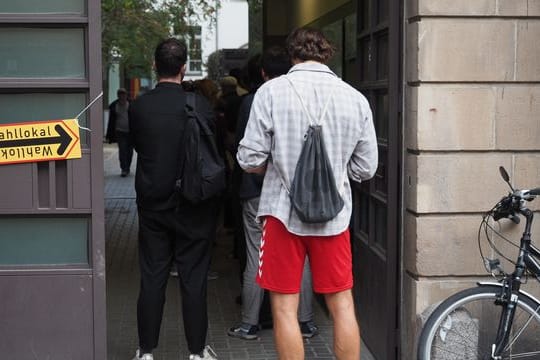 Wahlberechtigte warten deutlich nach 18 Uhr in einer Schlange vor einem Wahllokal an der Mandelstraße im Berliner Stadtteil Prenzlauer Berg darauf, ihre Stimmen abgeben zu dürfen.