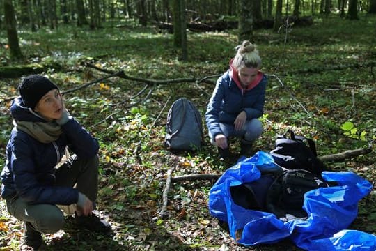 Maria Zlonkiewicz (l) und Aleksandra Gubinska knien nahe der polnisch-belarussischen Grenze neben Gegenständen, die von Flüchtlingen zurückgelassen wurden.