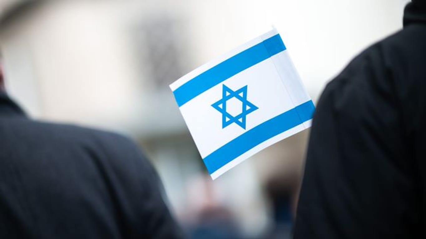 Bei einer Solidaritätskundgebung vor einer Synagoge hält ein Teilnehmer eine israelische Flagge in der Hand.