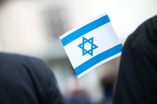 Bei einer Solidaritätskundgebung vor einer Synagoge hält ein Teilnehmer eine israelische Flagge in der Hand.