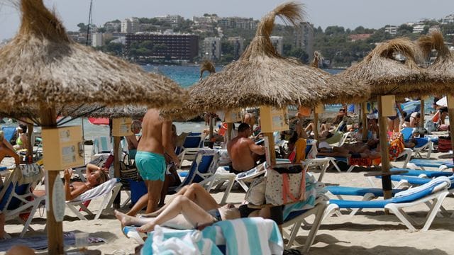 Einheimische und Touristen liegen am Strand Cala Major in Palma de Mallorca.