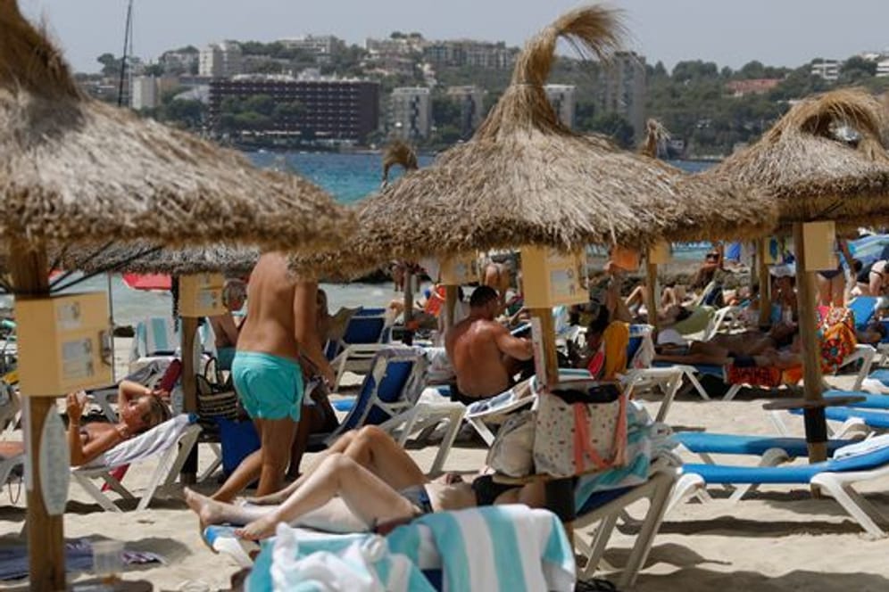 Einheimische und Touristen liegen am Strand Cala Major in Palma de Mallorca.