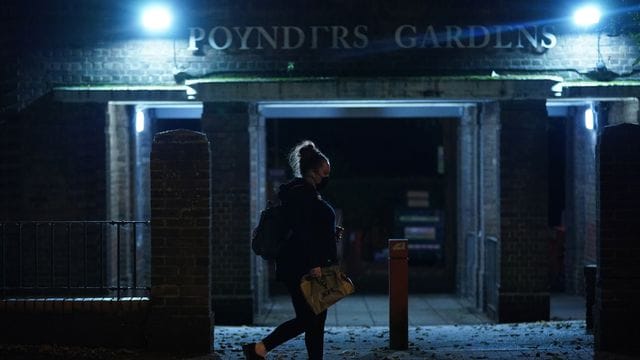 Eine Frau läuft nach Einbruch der Dunkelheit allein durch Südlondon. Eine Frau läuft nach Einbruch der Dunkelheit allein durch Südlondon.