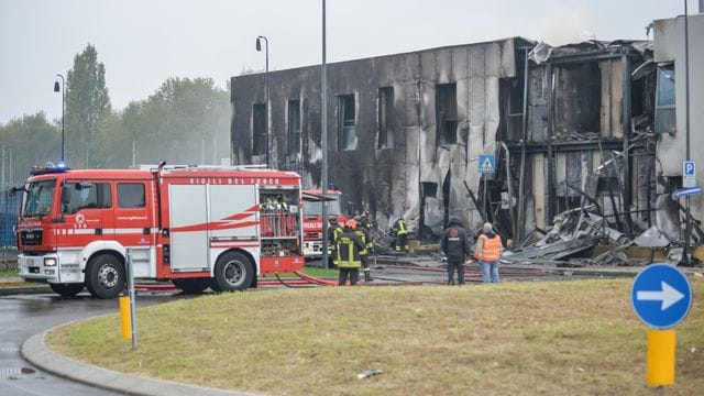 Feuerwehrleute stehen an der Unfallstelle, nachdem ein Leichtflugzeug kurz nach dem Start abgestützt und in ein leerstehendes Bürogebäude gekracht ist.