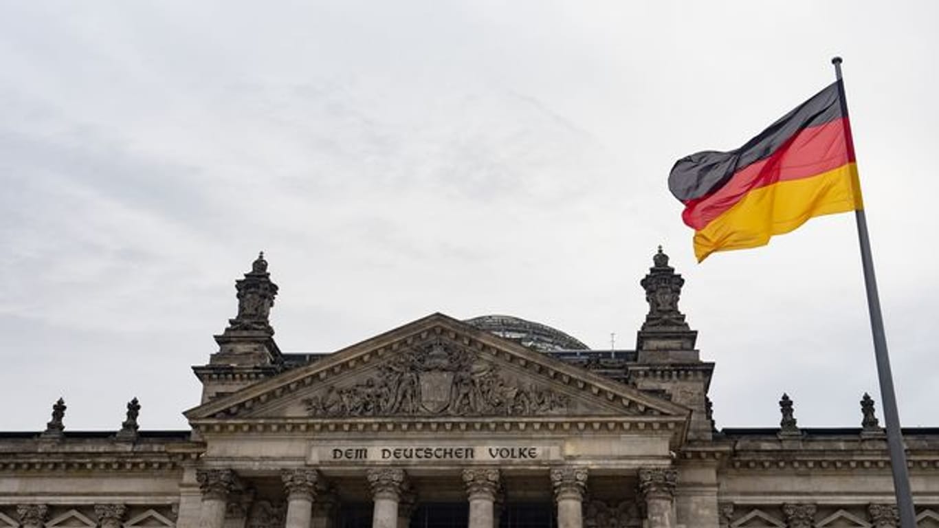 Eine Deutschland-Fahne weht am Tag der deutschen Einheit vor dem Reichstag.