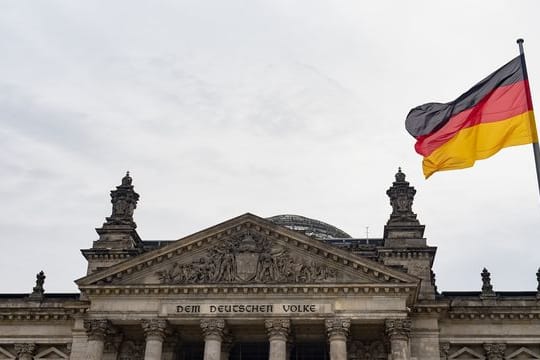 Eine Deutschland-Fahne weht am Tag der deutschen Einheit vor dem Reichstag.