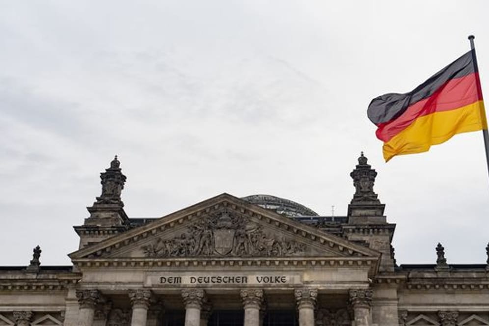 Eine Deutschland-Fahne weht am Tag der deutschen Einheit vor dem Reichstag.