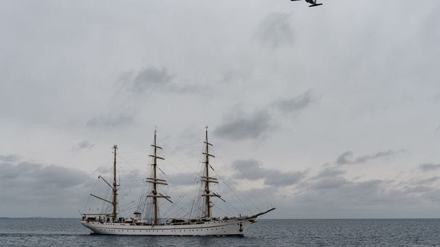 Das Segelschulschiff "Gorch Fock" fährt auf die Kieler Förde zu, während eine Transall der Bundeswehr das Schiff überfliegt.