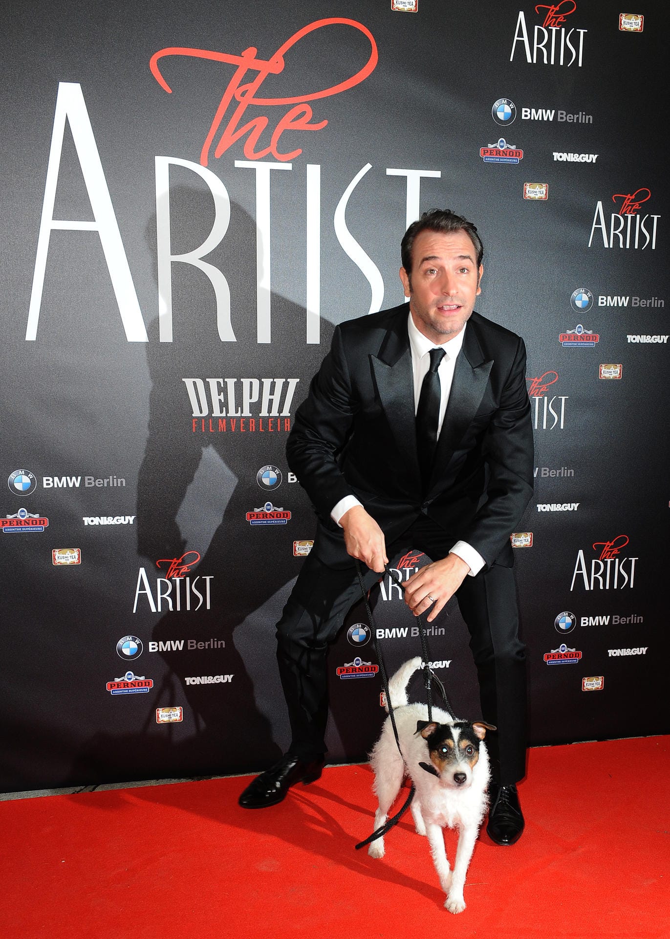 Der französische Schauspieler Jean Dujardin kommt mit dem Filmhund Uggie über den roten Teppich zur Deutschlandpremiere des Films "The Artist".