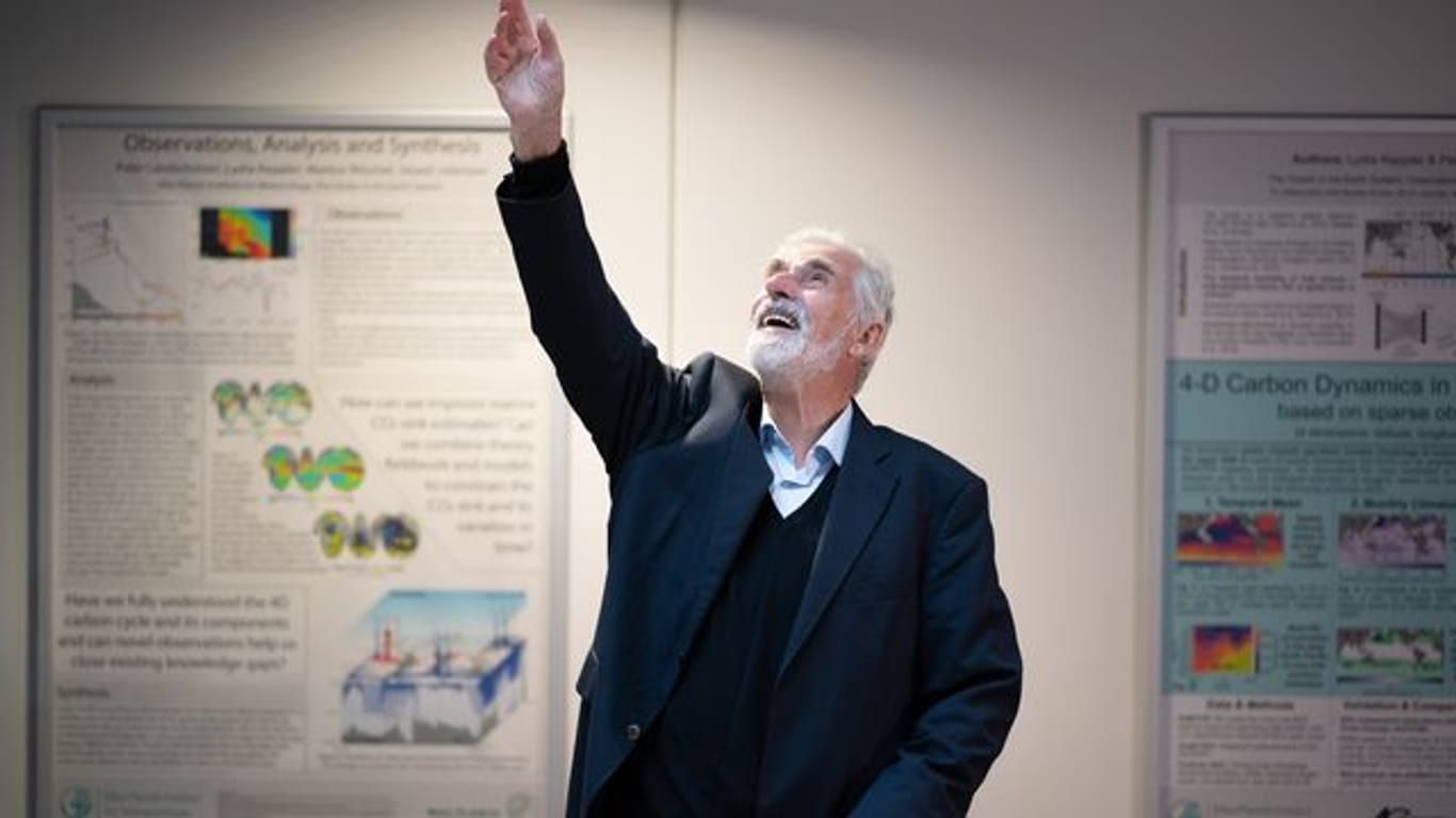 Klaus Hasselmann winkt im Max-Planck-Institut für Meteorologie in Hamburg jubelnden Mitarbeitenden zu.