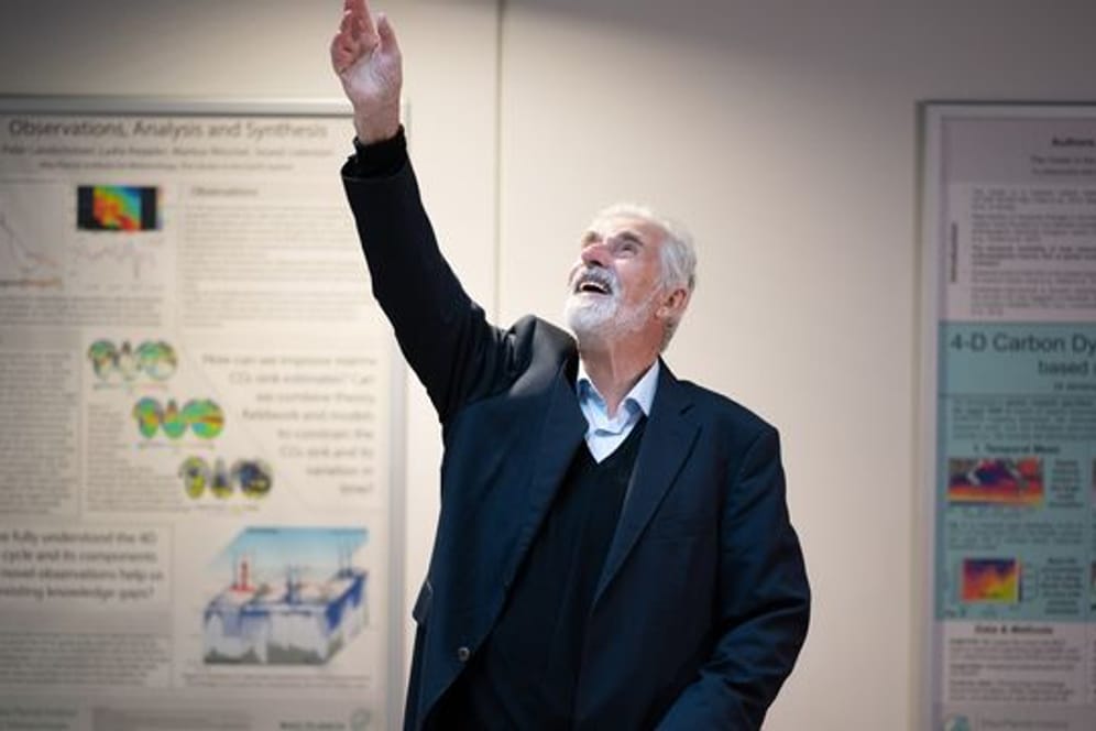 Klaus Hasselmann winkt im Max-Planck-Institut für Meteorologie in Hamburg jubelnden Mitarbeitenden zu.
