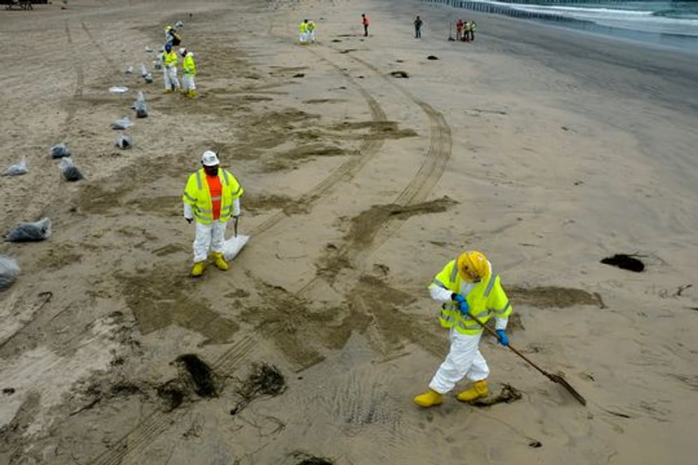 Arbeiter in Schutzanzügen reinigen den Strand nach einem Ölaustritt in Newport Beach, Kalifornien.