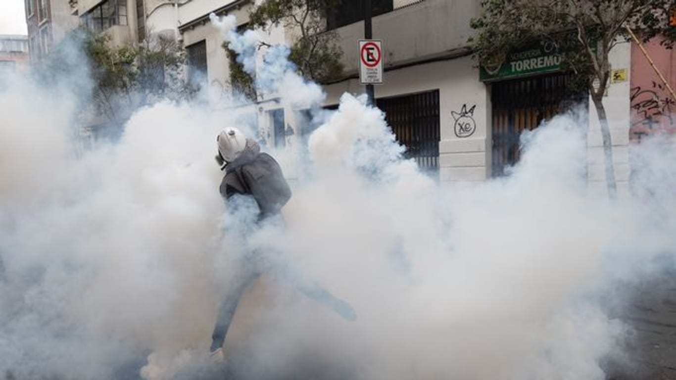 Ein Demonstrant wirft einen Tränengaskanister zurück, der von der Polizei abgefeuert wurde, um einen Protest in Santiago aufzulösen.