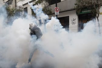 Ein Demonstrant wirft einen Tränengaskanister zurück, der von der Polizei abgefeuert wurde, um einen Protest in Santiago aufzulösen.