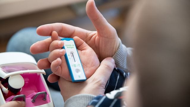 Ein Kita-Kind und seine Mutter warten daheim auf das Ergebnis eines Corona-Selbsttests.