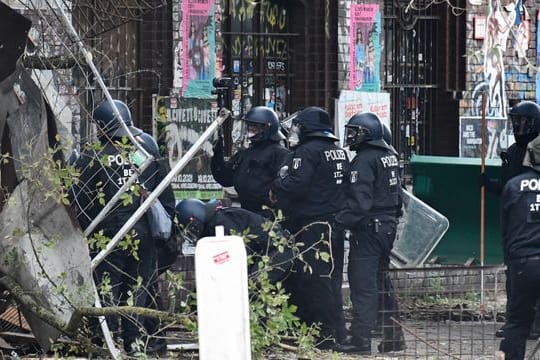 Polizisten räumen Barrikaden am Eingang der Bauwagensiedlung aus dem Weg.