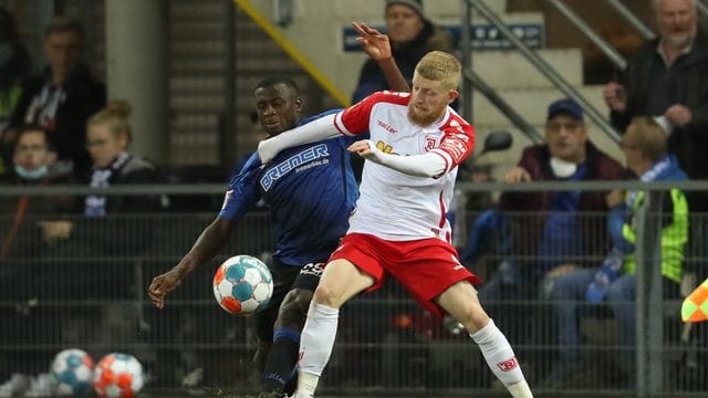 Paderborns Jamilu Collins (l) und Regensburgs Jan-Niklas Beste kämpfen energisch um den Ball.