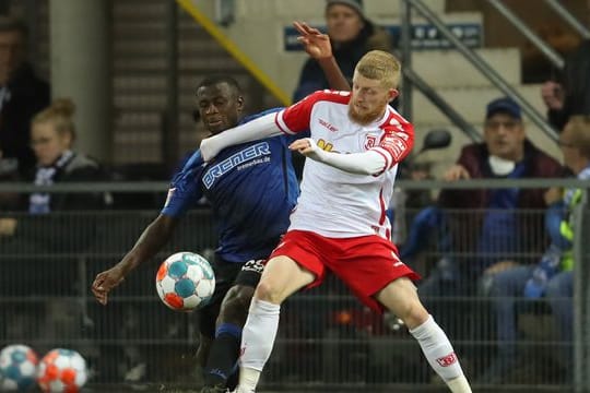 Paderborns Jamilu Collins (l) und Regensburgs Jan-Niklas Beste kämpfen energisch um den Ball.