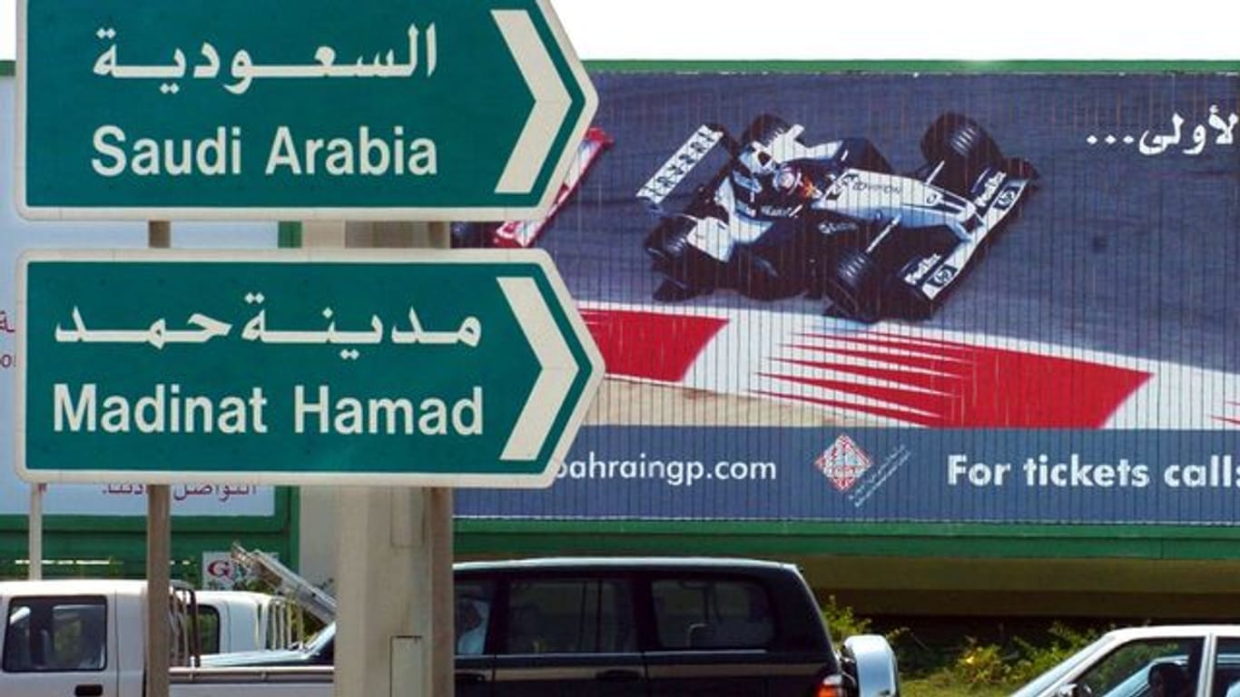 Hinweisschilder in Manama weisen vor einem Werbeplakat für die Formel 1 den Weg ins benachbarte Saudi Arabien.