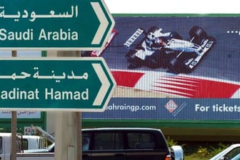 Hinweisschilder in Manama weisen vor einem Werbeplakat für die Formel 1 den Weg ins benachbarte Saudi Arabien.