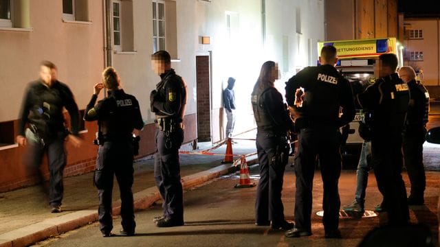 Polizisten und ein Rettungswagen vor dem Haus, in dem in der Nacht zum 19.