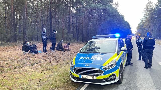 Bundespolizisten stehen neben einer Gruppe von Migranten, die zuvor über die deutsch-polnische Grenze gegangen waren.
