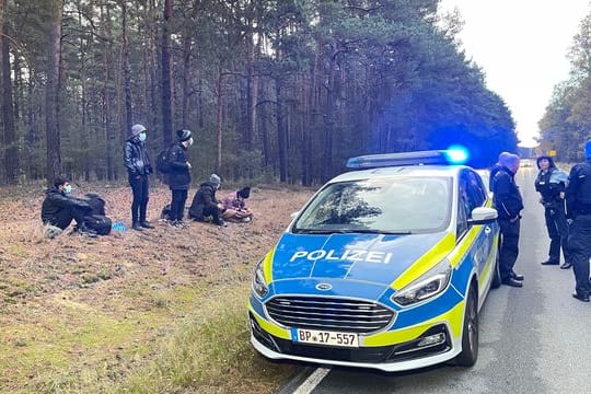 Bundespolizisten stehen neben einer Gruppe von Migranten, die zuvor über die deutsch-polnische Grenze gegangen waren.