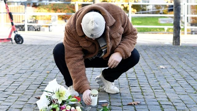 Ein Mann legt am Tatort Blumen und eine Kerze für den Musiker Einár nieder.