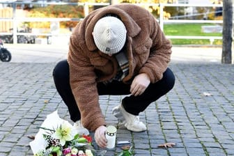 Ein Mann legt am Tatort Blumen und eine Kerze für den Musiker Einár nieder.