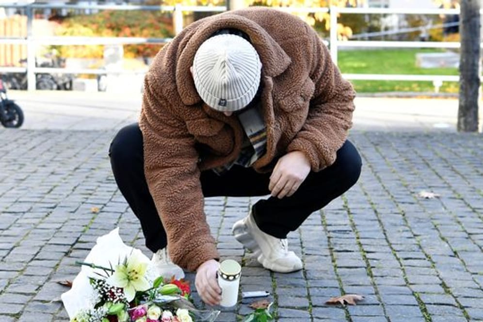 Ein Mann legt am Tatort Blumen und eine Kerze für den Musiker Einár nieder.