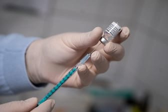 Ein Arzt zieht eine Spritze mit dem Impfstoff von Pfizer/Biontech auf.