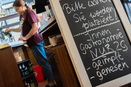 Eine Tafel mit der Aufschrift "Innengastronomie - Nur 2G - geimpft - genesen" steht in einem Gasthaus in Braunschweig.