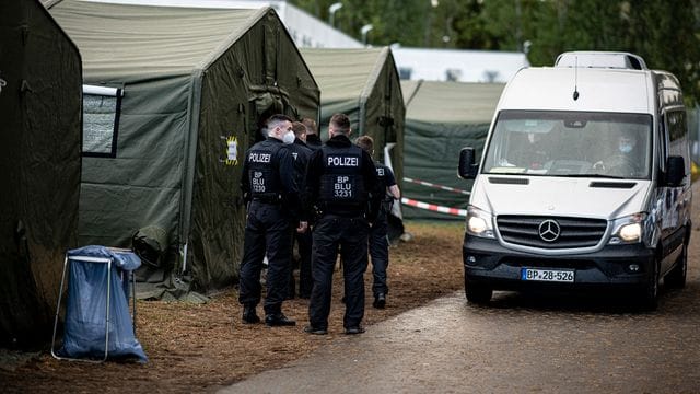 Polizisten in der Erstaufnahmeeinrichtung Eisenhüttenstadt neben einem Zelt für neu ankommende Asylsuchende.