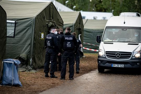 Polizisten in der Erstaufnahmeeinrichtung Eisenhüttenstadt neben einem Zelt für neu ankommende Asylsuchende.