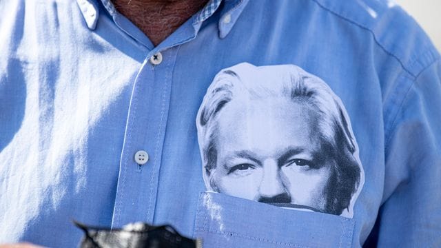 Ein Demonstrationsteilnehmer mit einer Maske des Wikileaks-Gründers Julian Assange im Hemd (Archivbild).