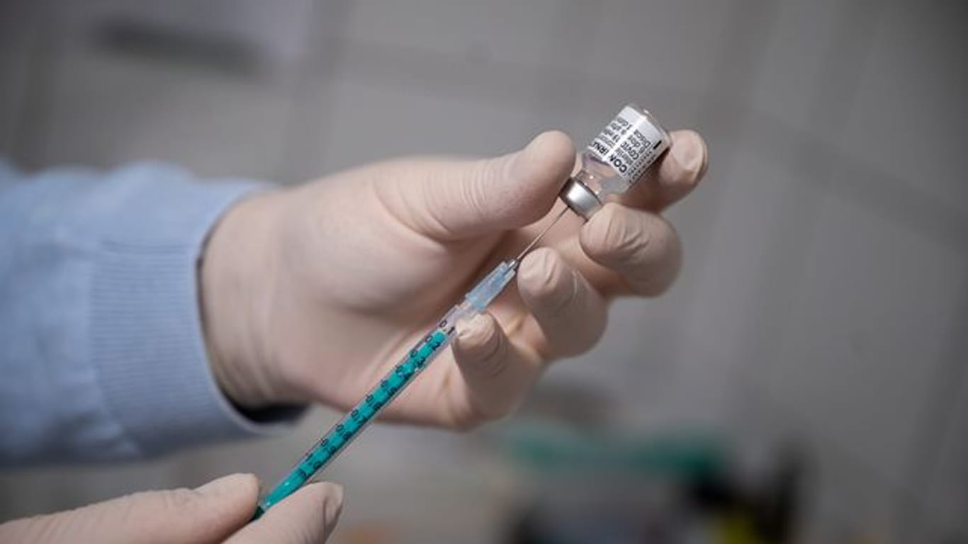 Ein Arzt zieht in einer Hausarztpraxis eine Spritze mit dem Impfstoff von Pfizer/Biontech auf.