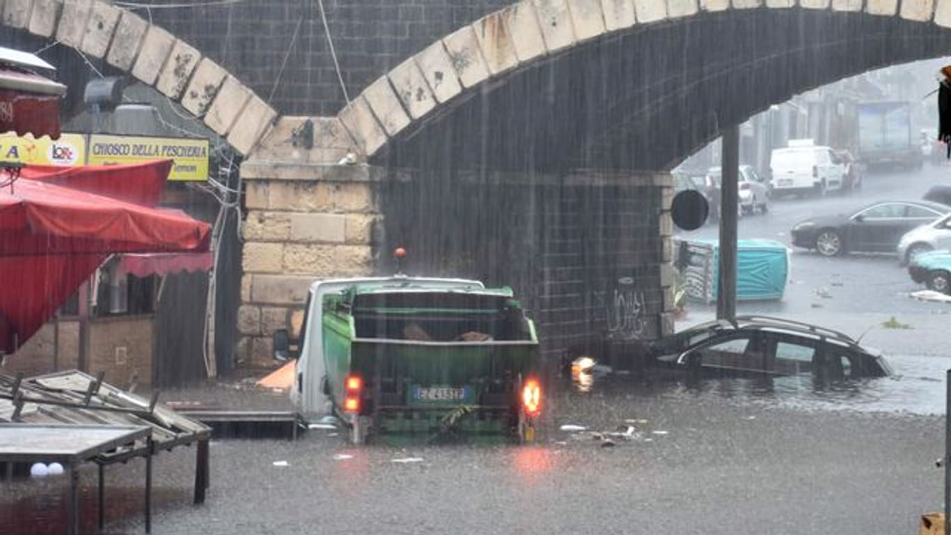 Fahrzeuge stehen auf einer überschwemmten Straße in Catania.