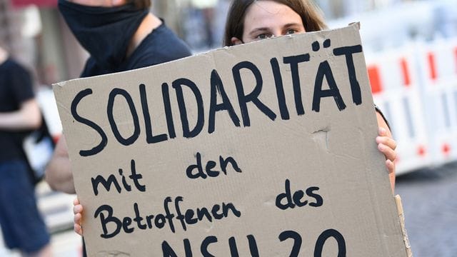 Eine Demonstrantin hält während einer Kundgebung in Wiesbaden ein Plakat mit der Aufschrift "Solidarität mit den Betroffenen des NSU 2. Eine Demonstrantin hält während einer Kundgebung in Wiesbaden ein Plakat mit der Aufschrift "Solidarität mit den Betroffenen des NSU 2.