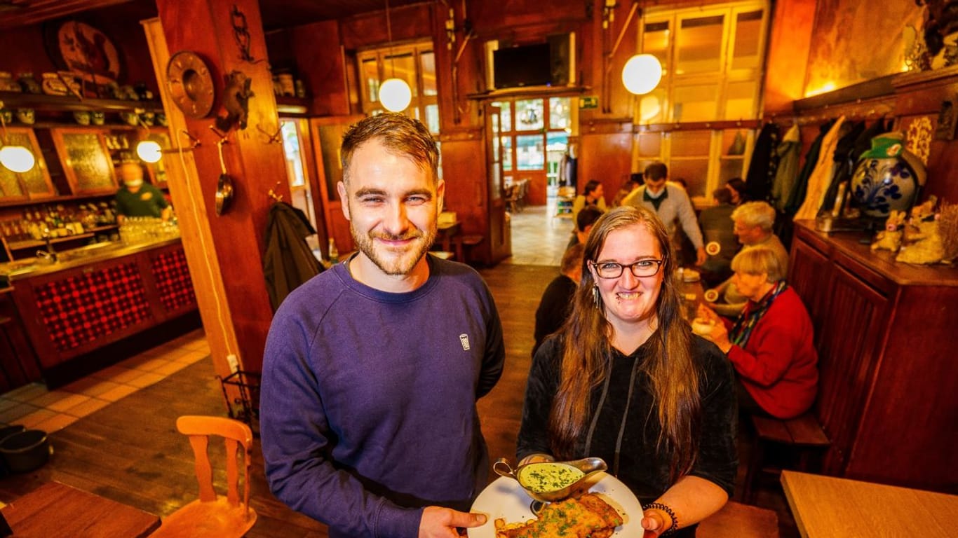 Robin Böhm, Junior Chef "Das Eichkatzerl", und Claudia Voigt, Küchenchefin, halten ein veganes "Frankfurter Schnitzel" mit veganer "Grüner Soße".