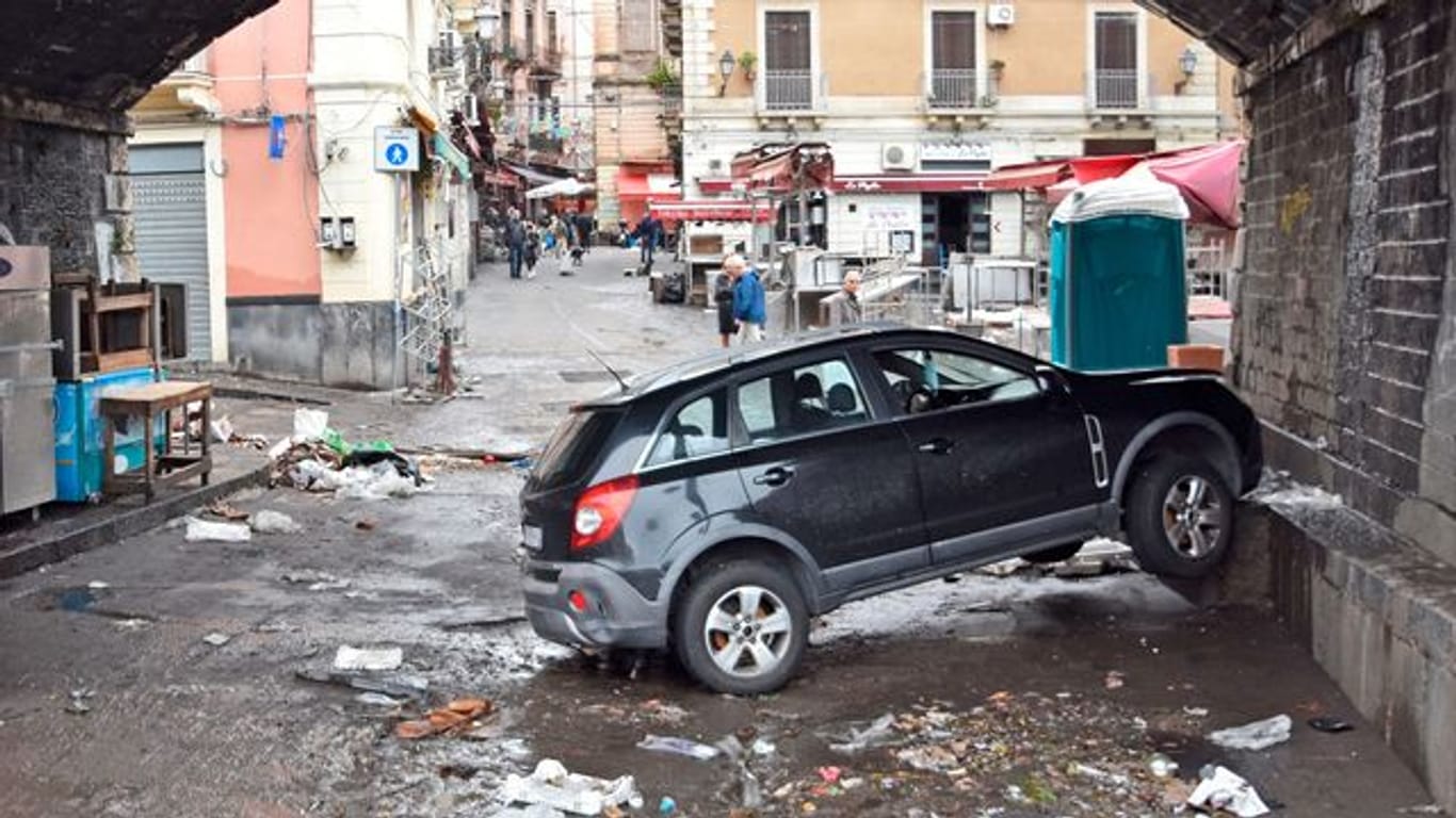 Ein Auto steckt, einen Tag nachdem Sizilien von einem heftigen Unwetter mit Überschwemmungen heimgesucht wurde, unter einer Unterführung an einer Mauer fest.