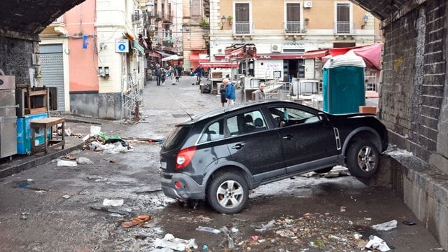 Ein Auto steckt, einen Tag nachdem Sizilien von einem heftigen Unwetter mit Überschwemmungen heimgesucht wurde, unter einer Unterführung an einer Mauer fest.