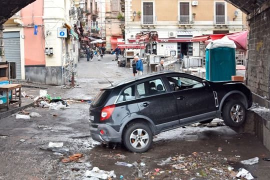 Ein Auto steckt, einen Tag nachdem Sizilien von einem heftigen Unwetter mit Überschwemmungen heimgesucht wurde, unter einer Unterführung an einer Mauer fest.