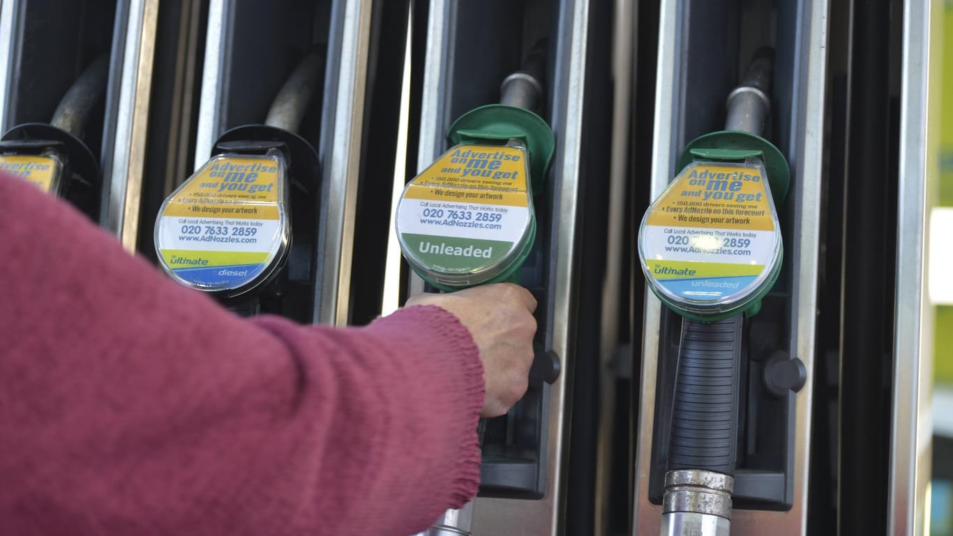 Eine Person greift nach dem Zapfhahn (Symbolbild): Autofahrer müssen an britischen Tankstellen aktuell tiefer in die Tasche greifen.