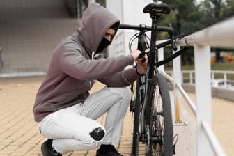 Fahrraddieb am Werk (Symbolbild): Kriminelle klauen die Fahrräder meist in der Stadt – hier haften die meisten Hausratversicherungen allerdings nicht.