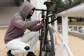 Fahrraddieb am Werk (Symbolbild): Kriminelle klauen die Fahrräder meist in der Stadt – hier haften die meisten Hausratversicherungen allerdings nicht.