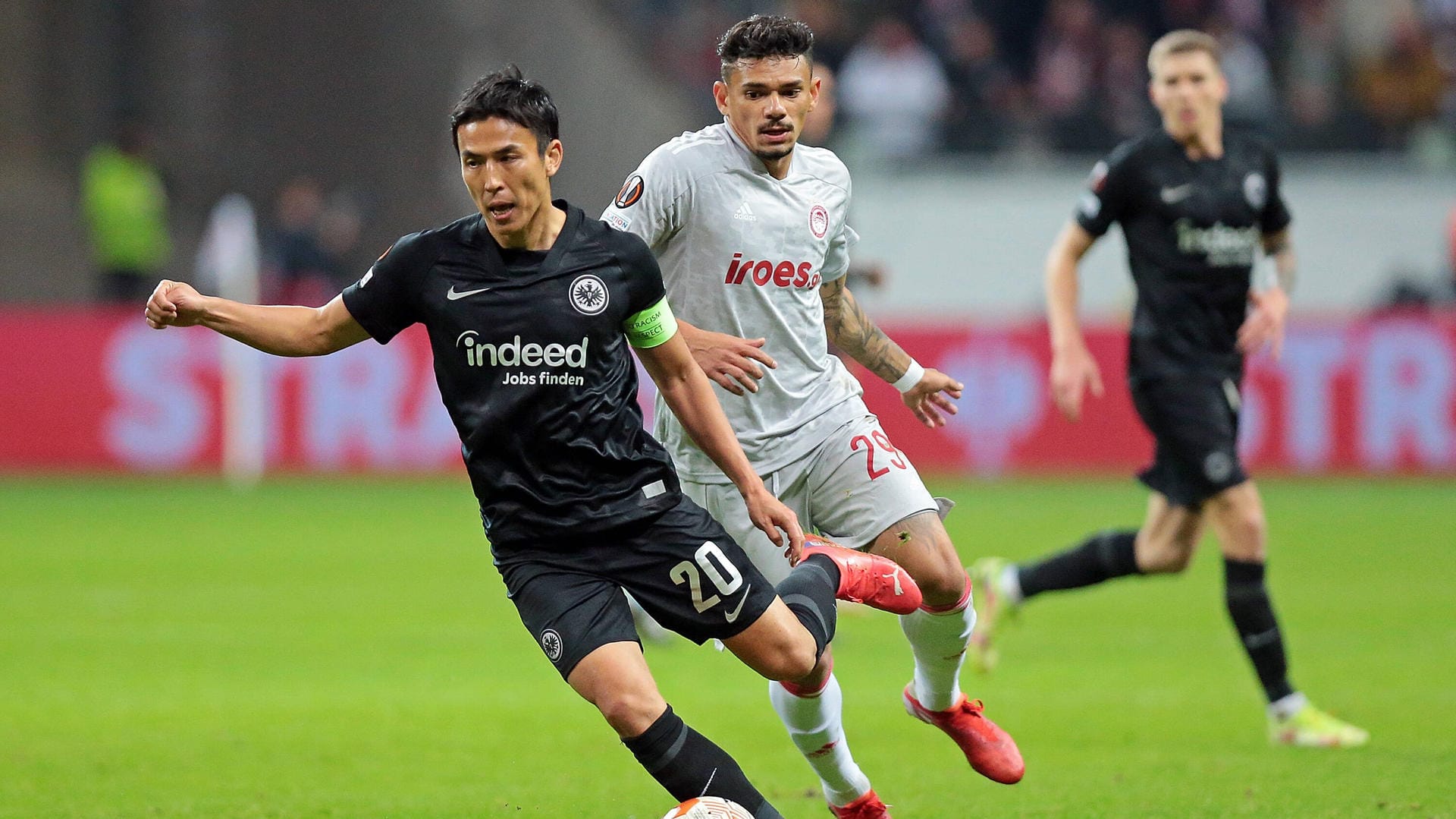 Frankfurts Makoto Hasebe (l.) will auch im Rückspiel in Piräus (rechts Tiquinho Soares) punkten und die Tabellenführung in der Europa League verteidigen.