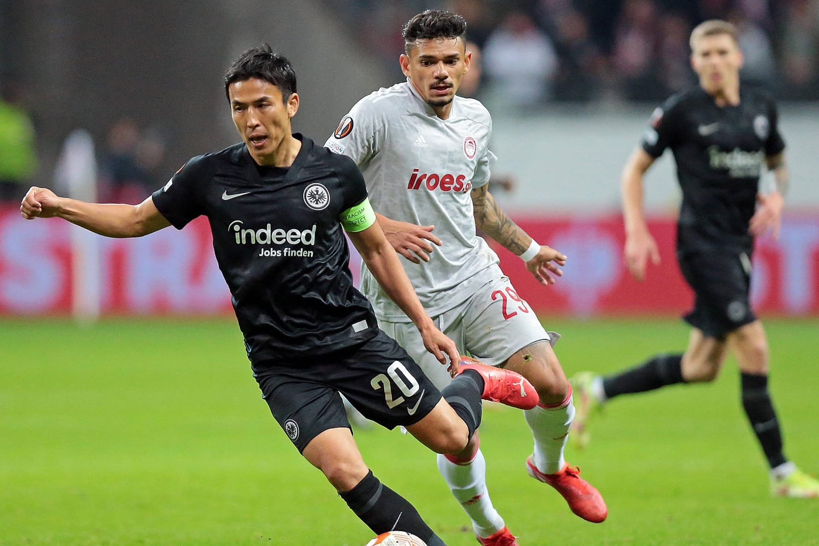 Frankfurts Makoto Hasebe (l.) will auch im Rückspiel in Piräus (rechts Tiquinho Soares) punkten und die Tabellenführung in der Europa League verteidigen.