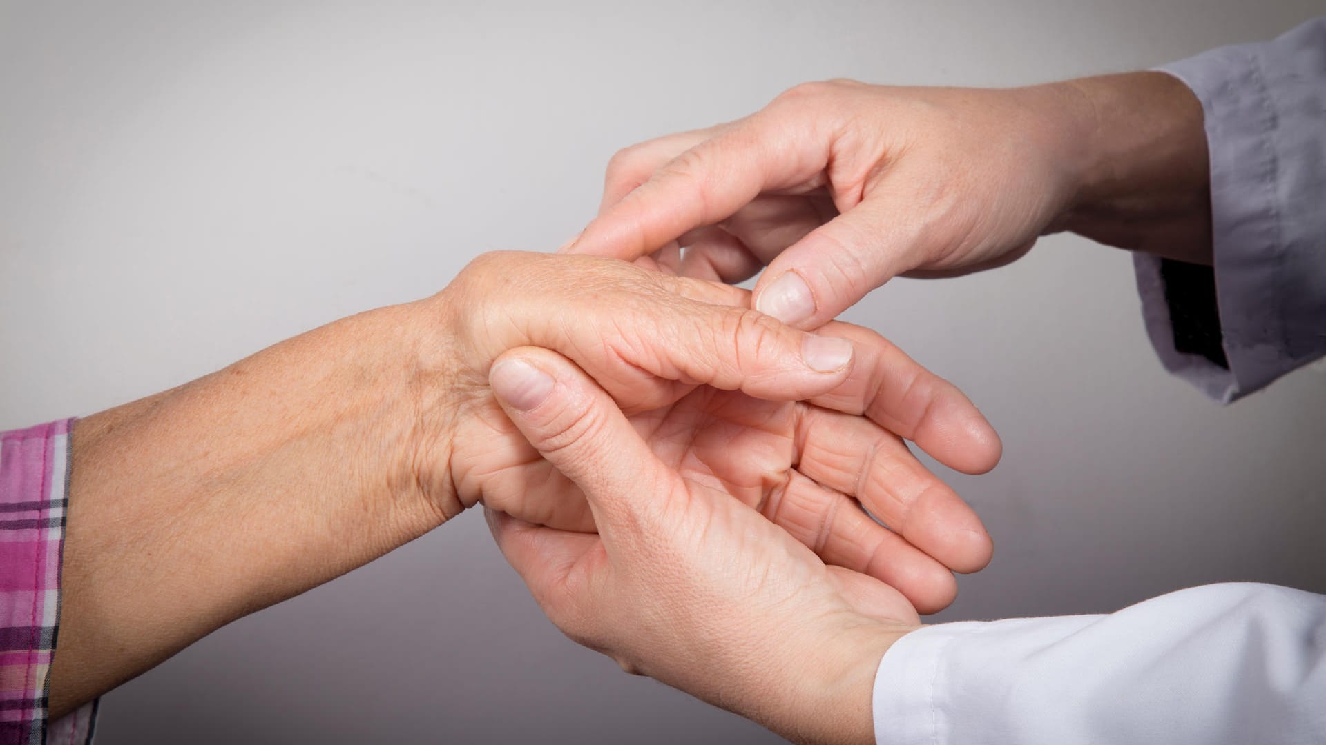 Arzt untersucht die Hand einer Patientin: Bei Verdacht auf Rhizarthrose wird die Ärztin oder der Arzt den betroffenen Daumen genau untersuchen.